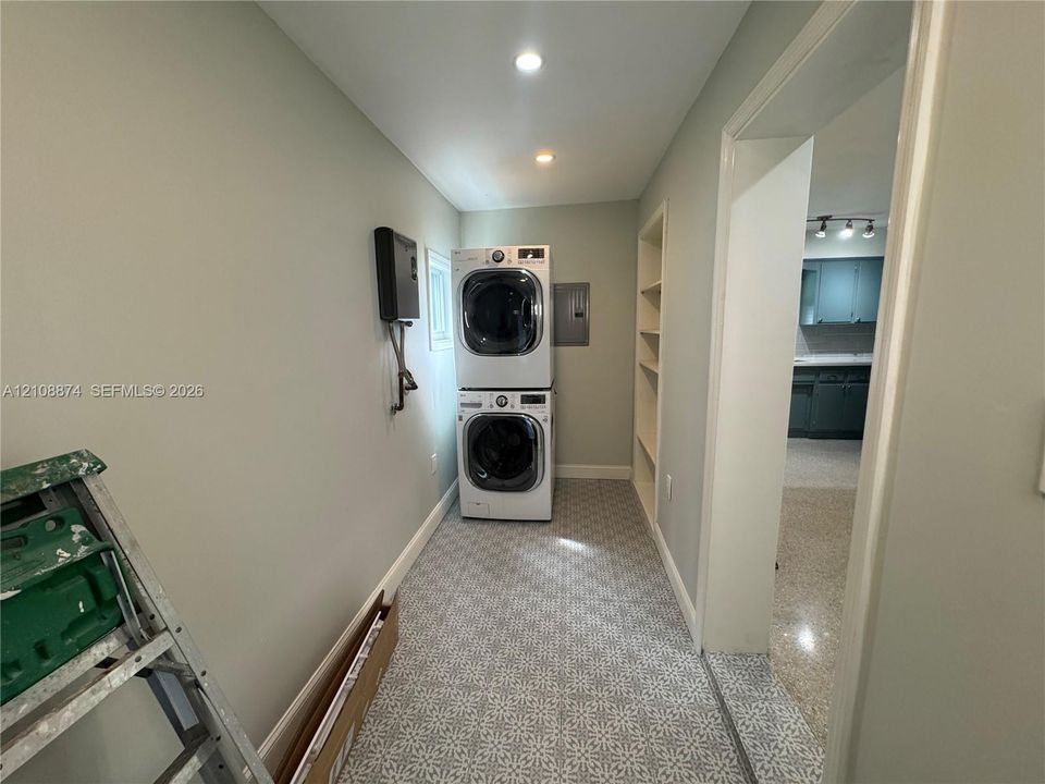 Laundry area featuring patterned tile flooring, built-in shelving, and recessed lighting