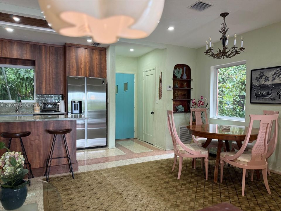 Kitchen featuring wood-finish cabinetry, stainless steel side-by-side refrigerator, built-in wall shelving, recessed lighting, and ornate chandelier
