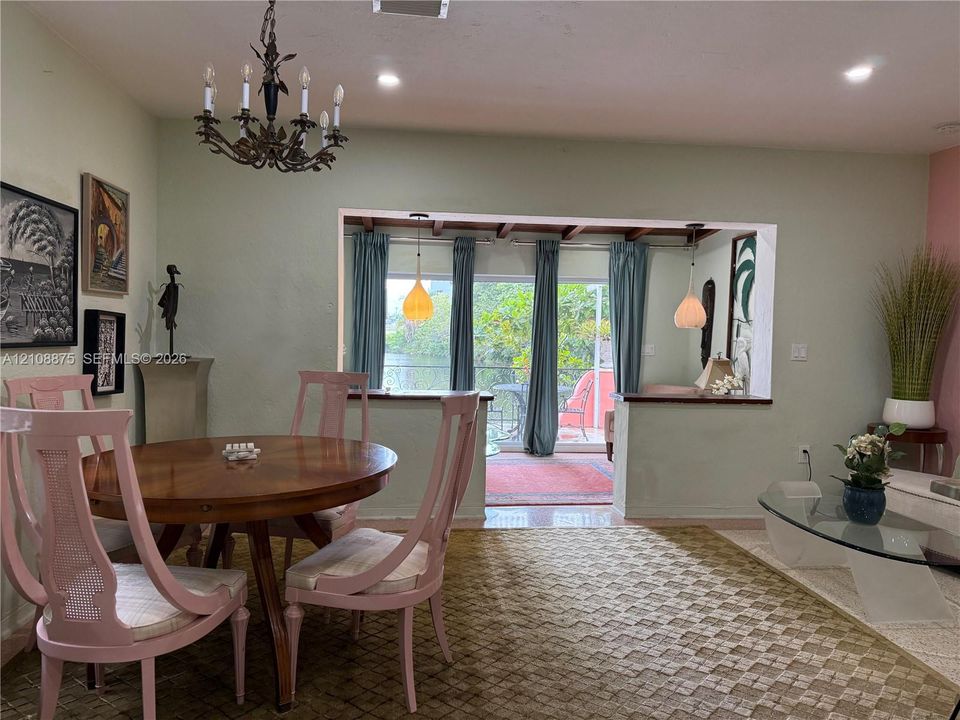 Dining area featuring a wrought iron chandelier, recessed lighting, and a large wall opening with a built-in ledge