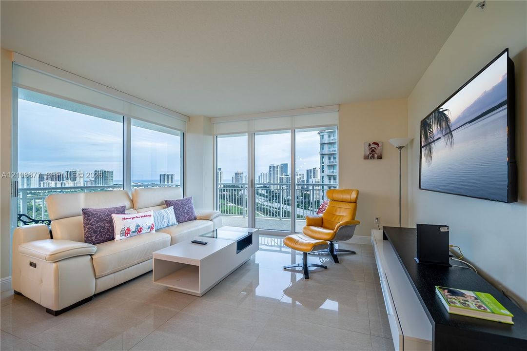 Living space featuring floor-to-ceiling glass windows, polished tile flooring, and a private balcony