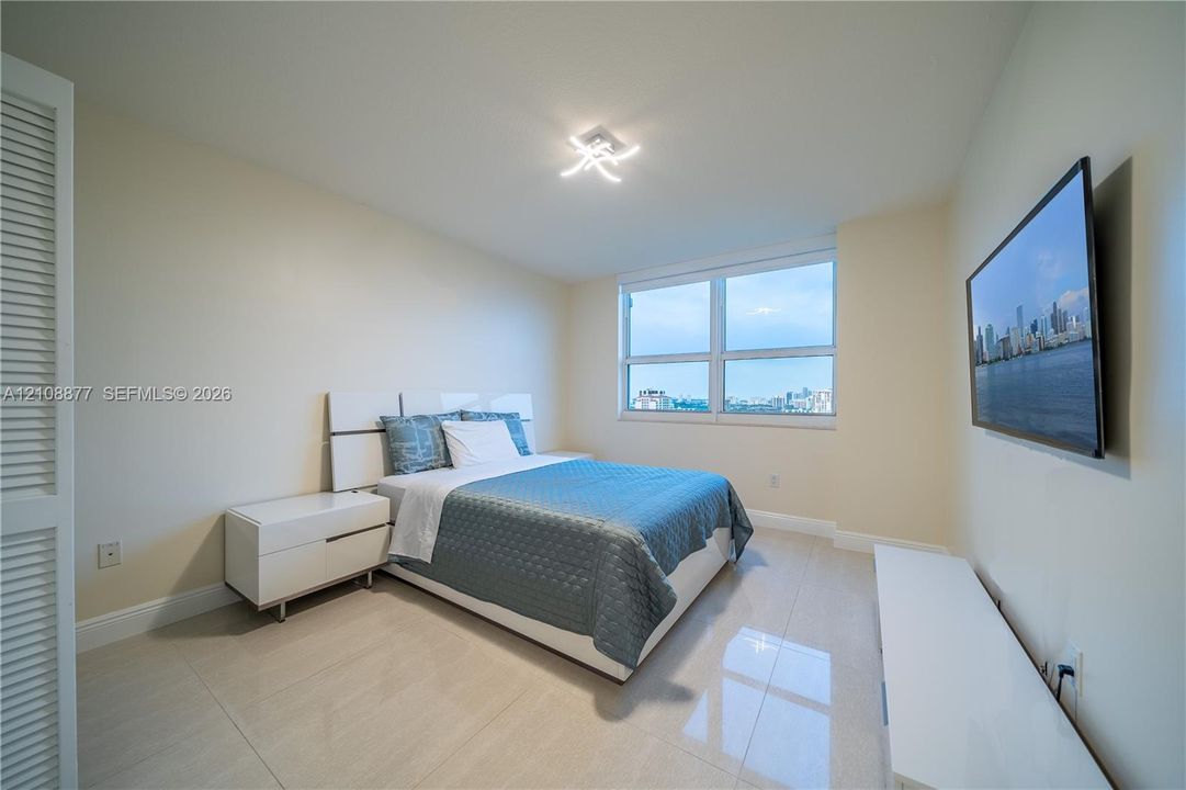 Interior space featuring large-format tile flooring, oversized picture window with urban skyline exposure, and modern contemporary multi-arm flush-mount ceiling light fixture
