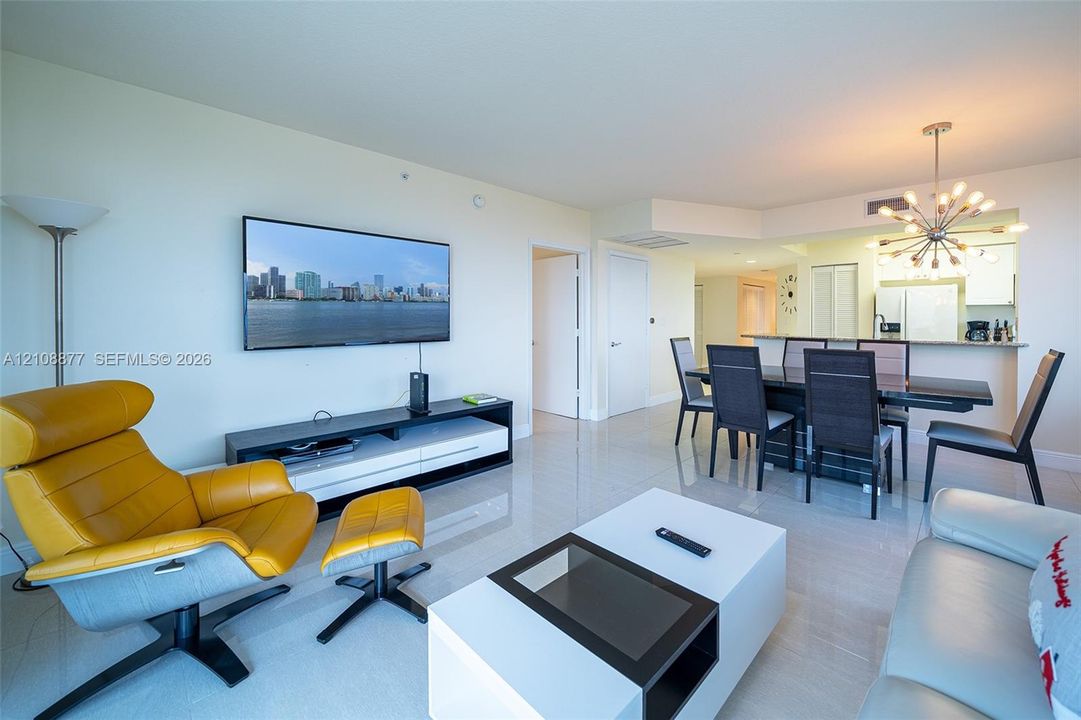 Open-concept living space featuring neutral tile flooring, recessed ceiling lighting, and a modern multi-bulb Sputnik-style chandelier