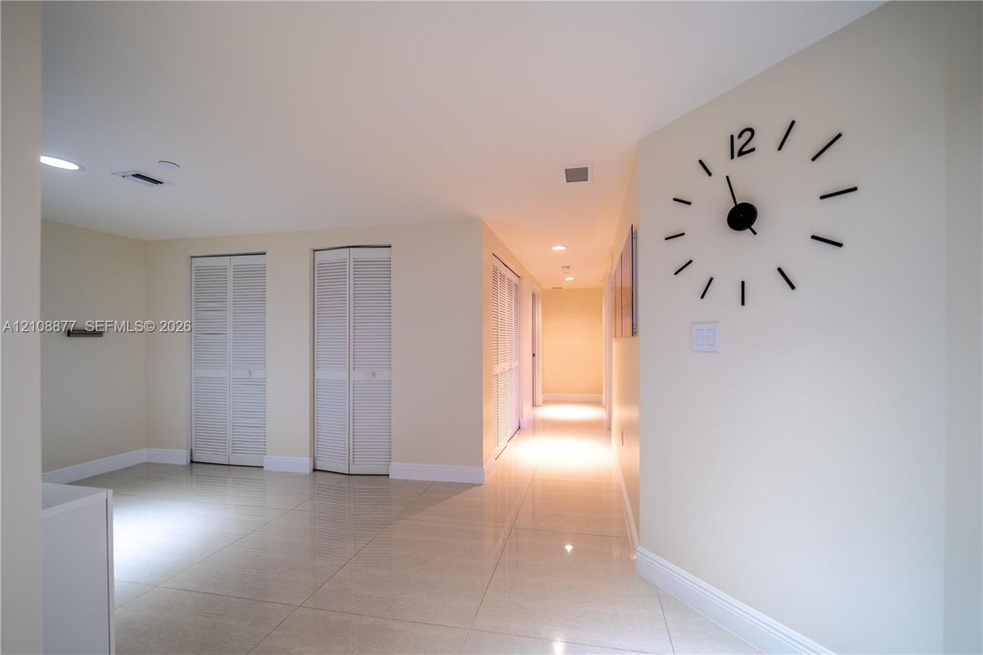 Large-format polished tile flooring, neutral wall tones, recessed lighting, and white louvered closet doors