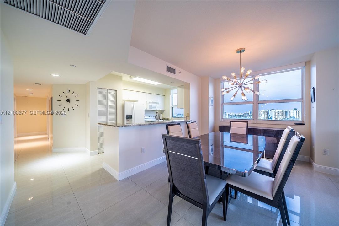 Open floor plan featuring polished tile flooring, a breakfast bar with stone-surface countertop, and a statement chandelier fixture