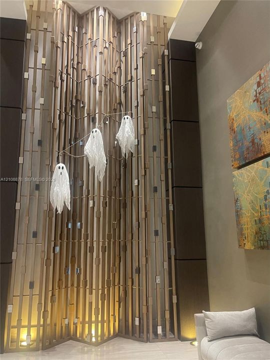 Floor-to-ceiling decorative wood slat wall feature with integrated recessed floor lighting and dark paneled column accents