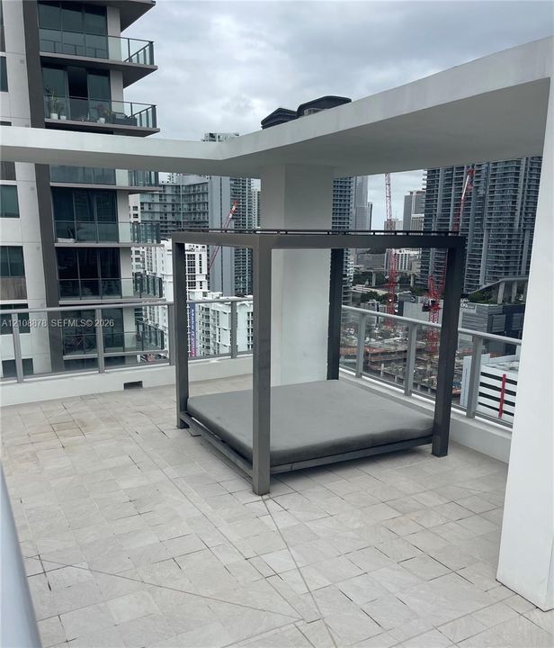 Rooftop terrace featuring large-format tile flooring, a concrete pergola structure, and a metal railing system