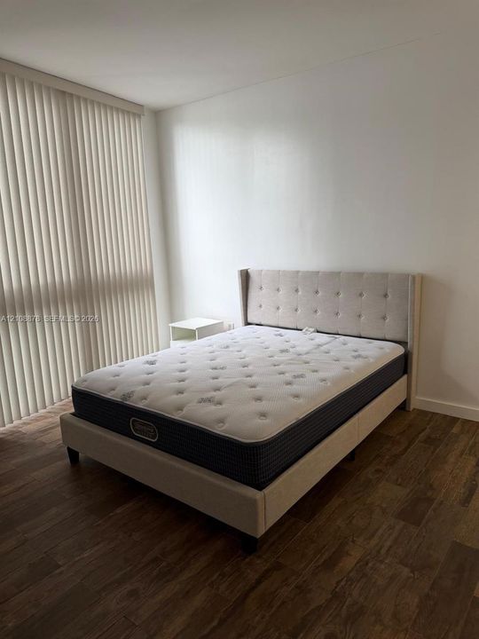 Room with wood-finish flooring and vertical window blinds