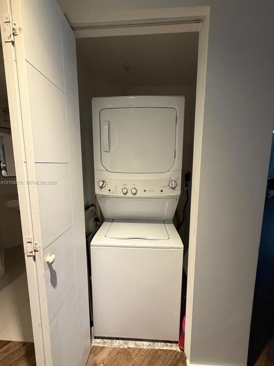 Stacked white laundry center featuring a top-loading washer and front-loading dryer enclosed within a closet