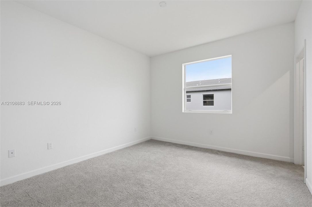Neutral-toned interior space featuring light-colored wall paint, wall-to-wall carpeting, and a single-pane window