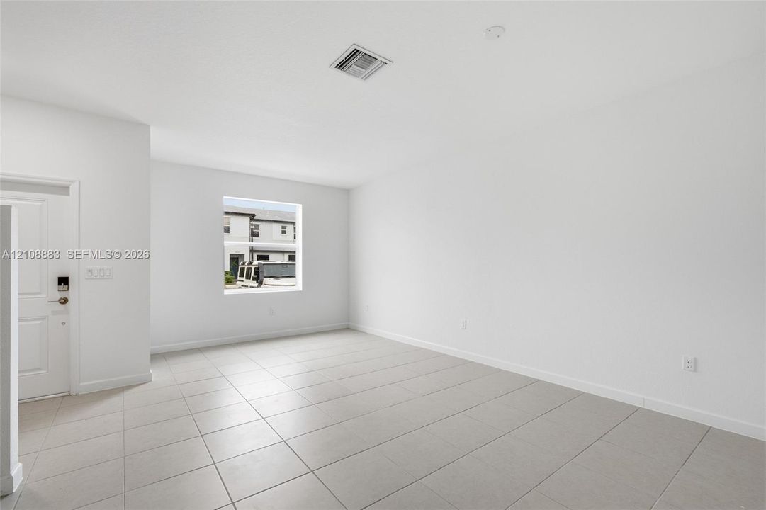 Interior space featuring neutral wall paint, large-format tile flooring, a multi-panel door with integrated lock hardware, and a single-pane window