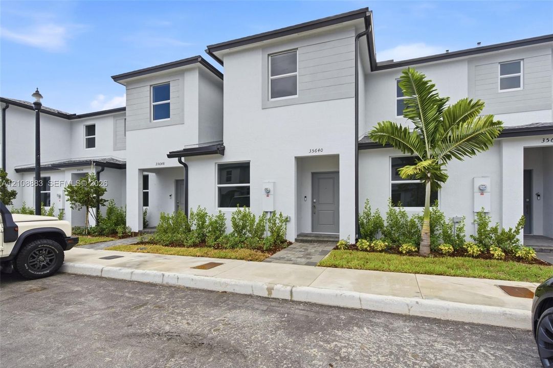Contemporary multi-story exterior featuring smooth stucco siding, horizontal lap accents, energy-efficient windows, and a paved stone walkway