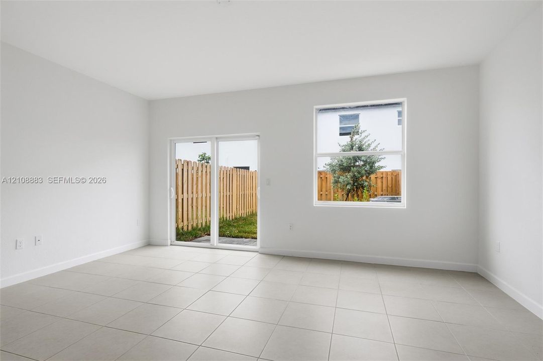 Neutral interior featuring large-format ceramic tile flooring, bright white walls, sliding glass door, and a dual-pane window