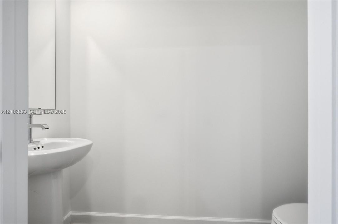 White pedestal sink featuring a polished chrome single-lever faucet and a rectangular wall-mounted mirror