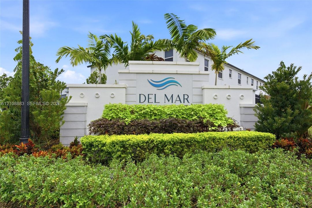 Custom-built masonry community entrance sign featuring tiered landscaping with palm trees and manicured shrubs