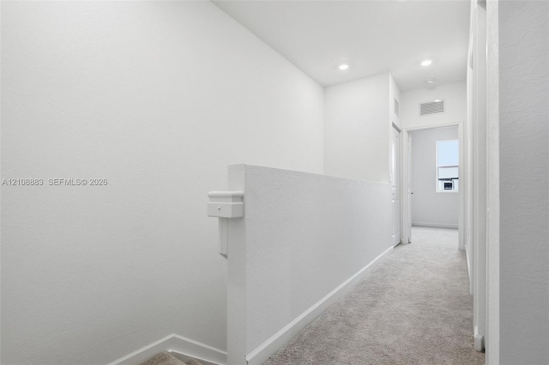 Neutral-toned wall-to-wall carpeting, solid half-wall partition, and recessed ceiling lighting
