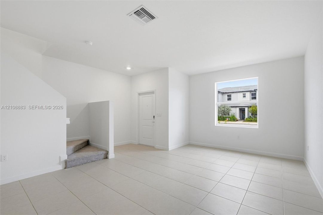 Open-concept interior featuring large-format tile flooring, recessed lighting, and a single-hung window