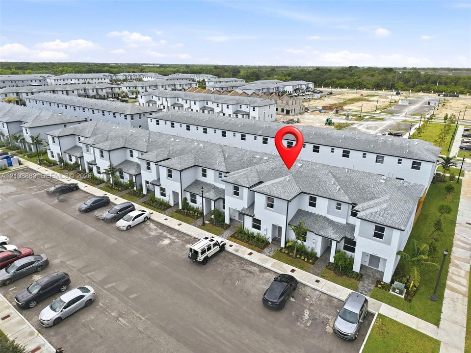 Multi-story townhouse featuring a light-toned exterior finish, composite shingle roofing, and dedicated exterior parking