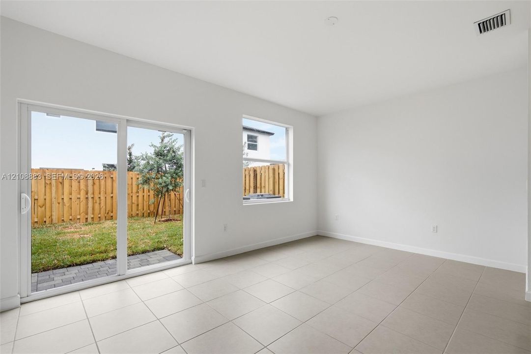 Interior space featuring large format neutral tile flooring, sliding glass patio door, and single-pane window
