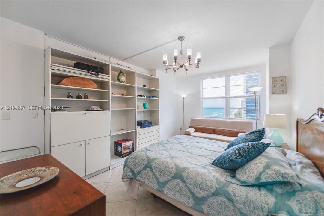Built-in white storage cabinetry, tiled flooring, multi-pane window, and a decorative overhead light fixture