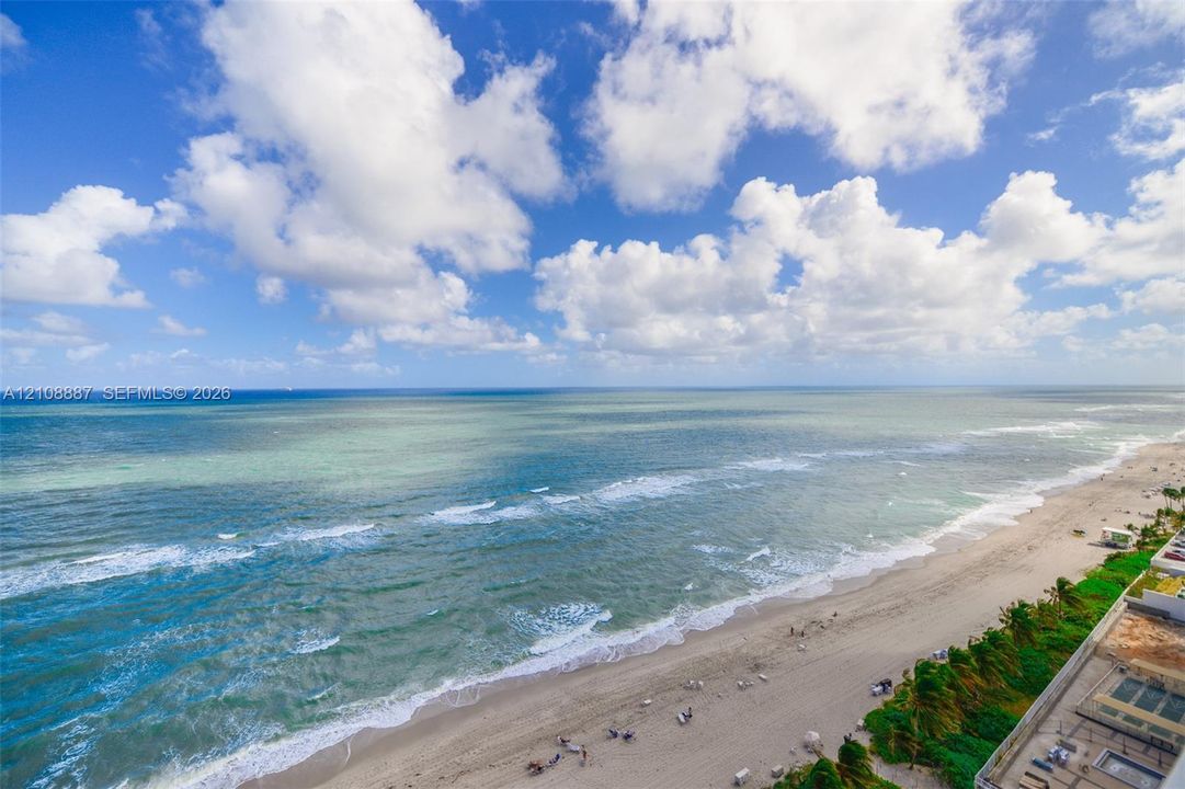Elevated perspective of the coastline featuring expansive ocean frontage and direct access to the sandy beach