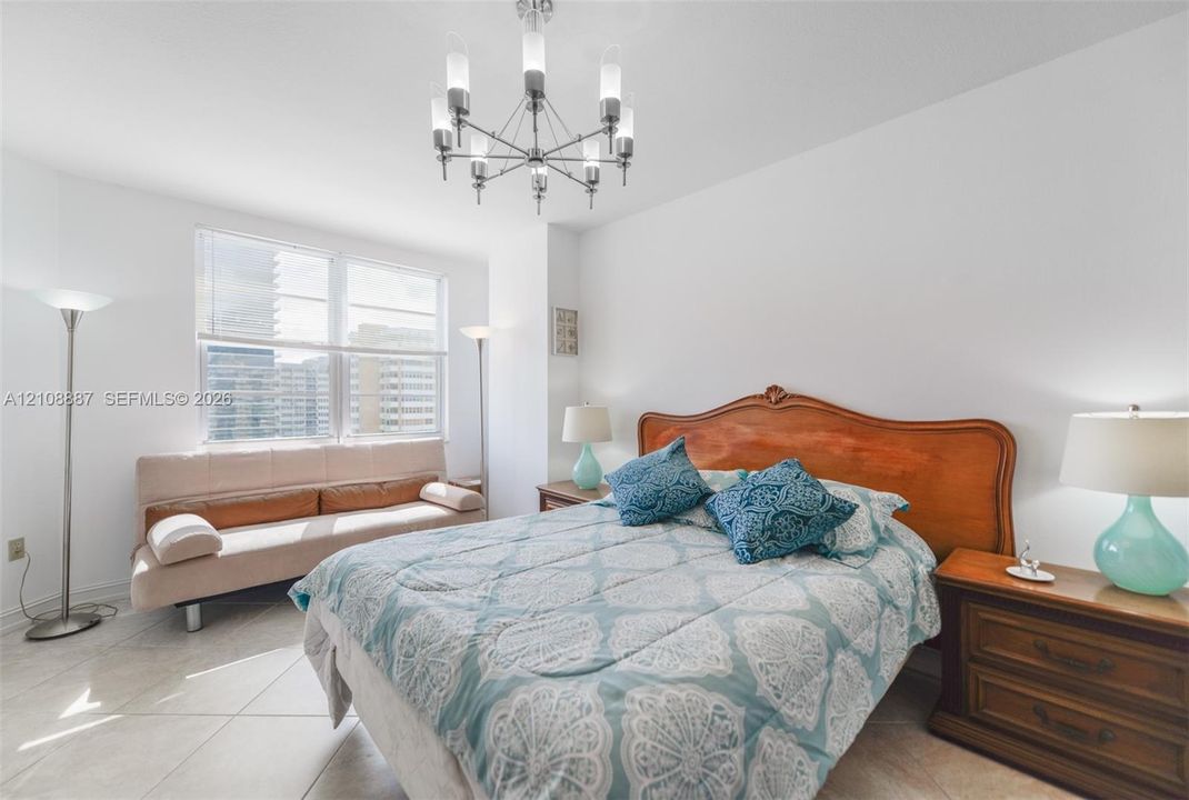 Large window with exterior urban scenery, tile flooring, and multi-arm chandelier