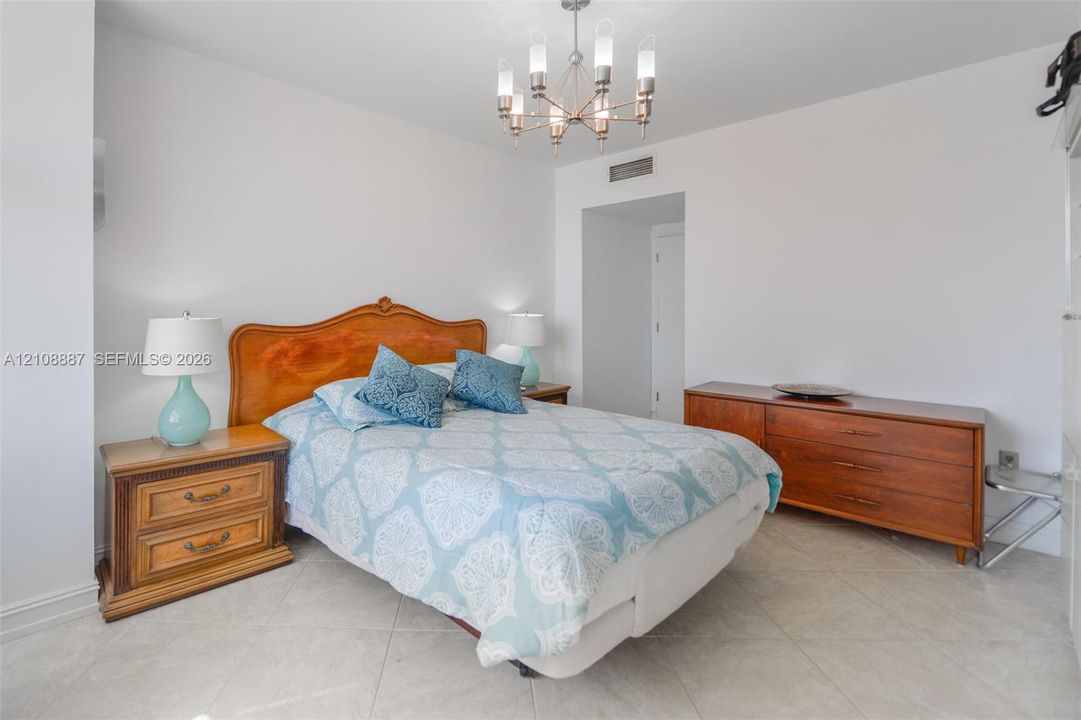 Room featuring tile flooring and a multi-arm metallic chandelier with frosted glass shades