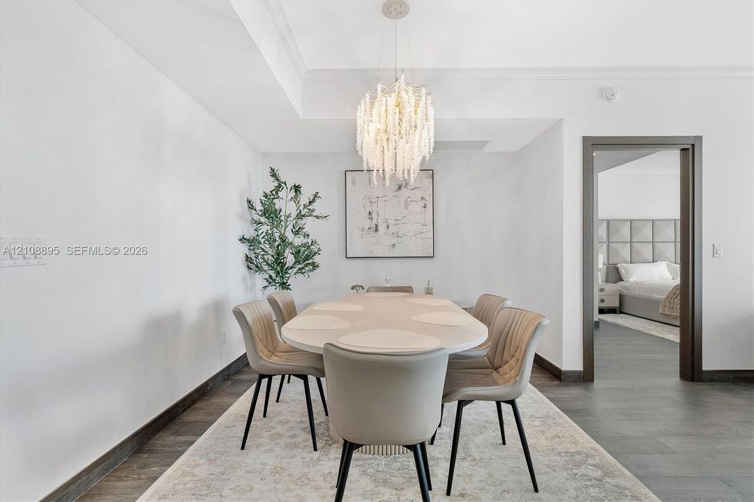 Dining area featuring charcoal tile flooring, recessed ceiling detail, and a tiered crystal chandelier