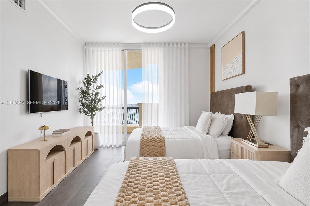 Floor-to-ceiling glass sliding doors opening to a balcony, dark wood-finish flooring, and a modern circular LED light fixture