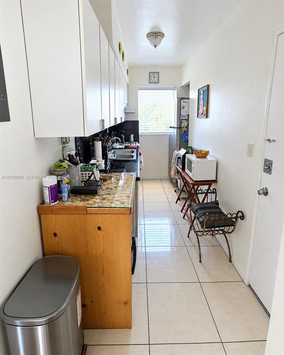 Kitchen featuring white cabinetry, dark countertops, a built-in metal sink with a faucet, and large-format tile flooring