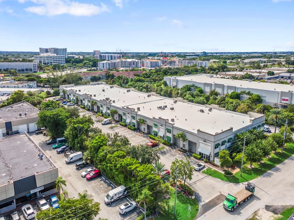 Multi-unit commercial structure featuring concrete tilt-wall construction, flat roofline, paved surface parking, and mature perimeter landscaping
