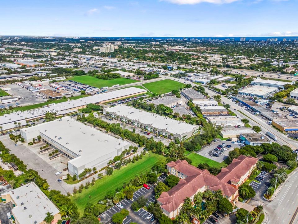 Aerial perspective of industrial facility featuring expansive parking areas, multiple loading bays, flat roofing, and proximity to major arterial roadways
