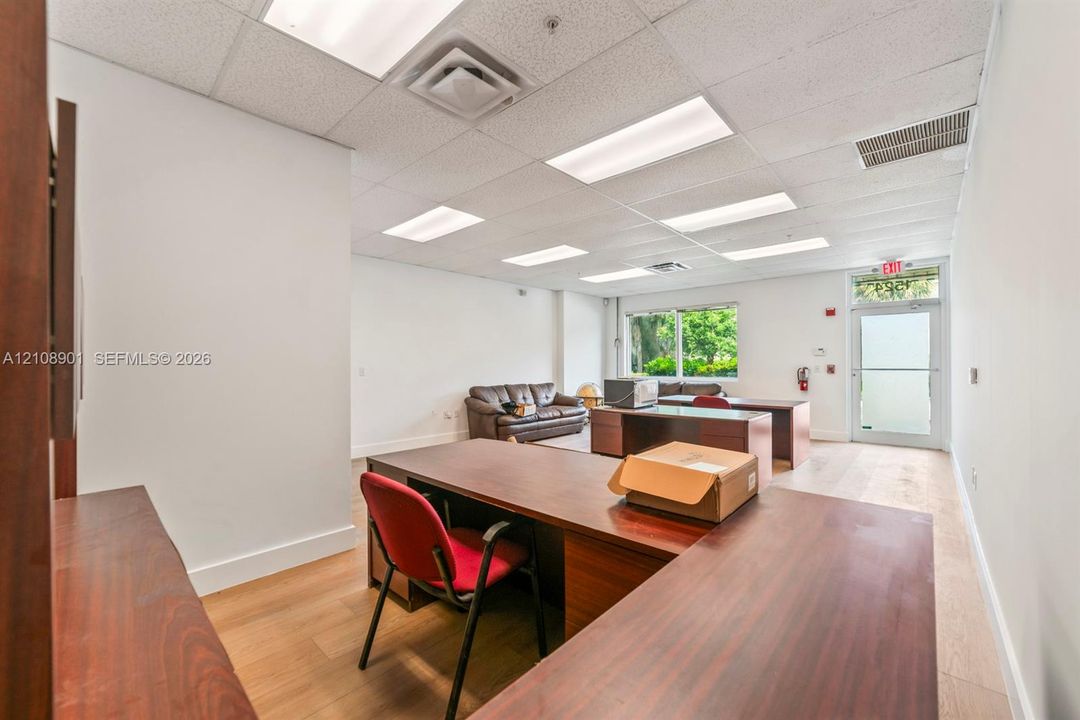Open-concept interior featuring wood-finish flooring, recessed lighting, drop ceiling panels, and a glass-paneled exterior entry door