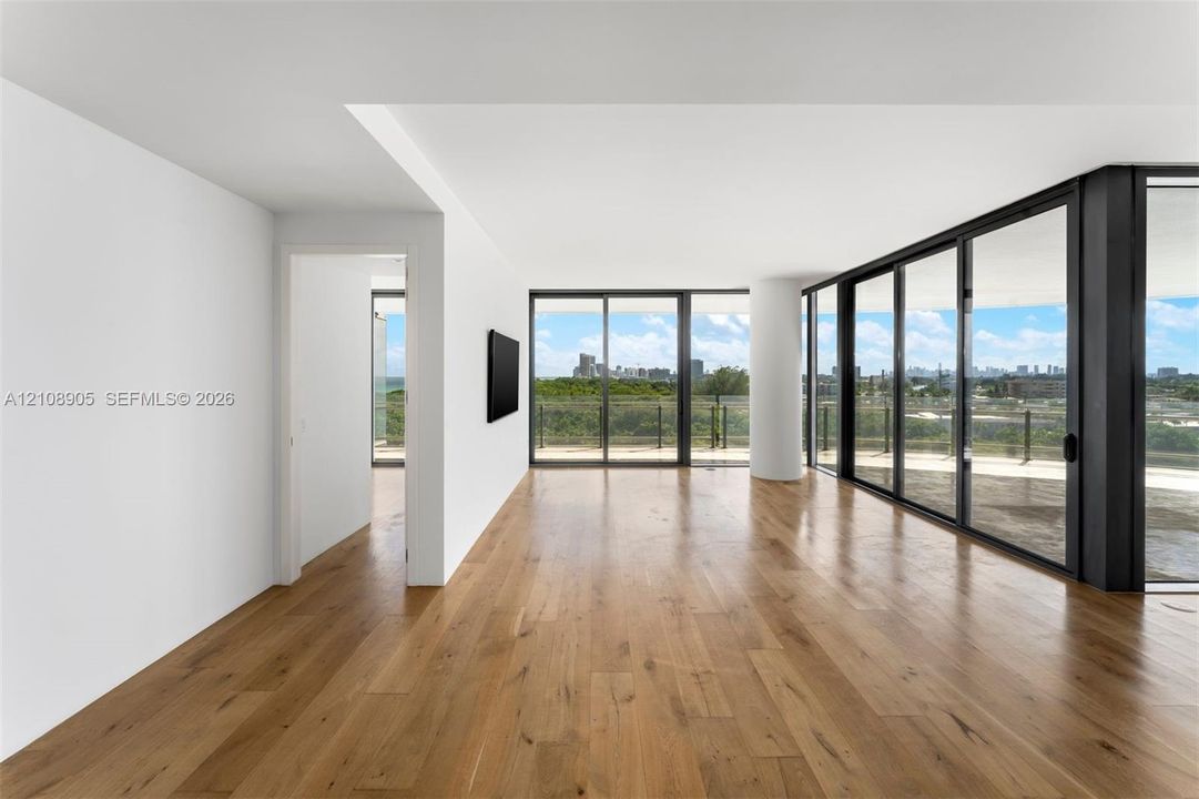 Floor-to-ceiling glass sliding doors, wood-finish flooring, expansive balcony, and structural column
