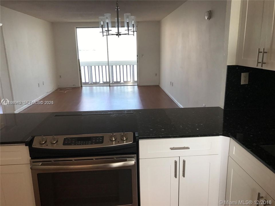 Kitchen featuring white shaker-style cabinetry, black countertops, and a stainless steel slide-in range