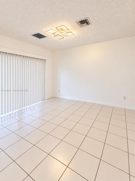 Room featuring large-format ceramic tile flooring, vertical window blinds, and a contemporary multi-square LED ceiling light fixture