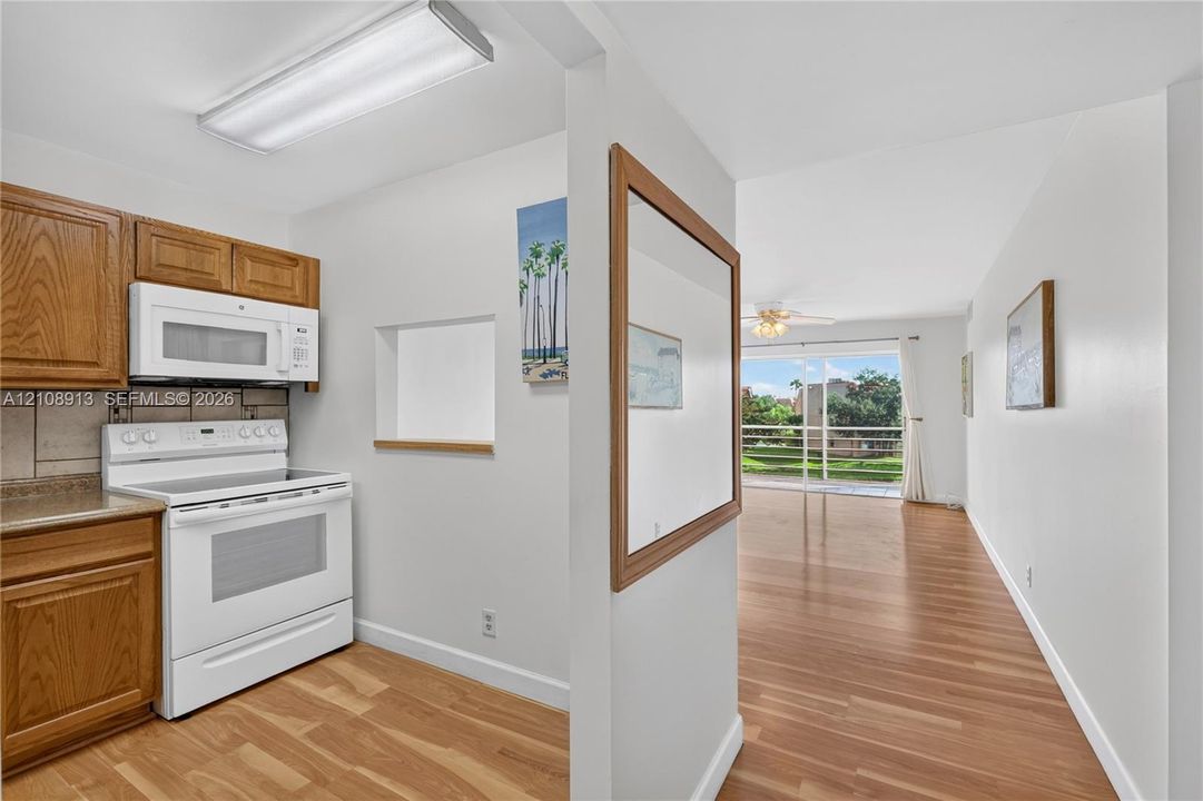 Kitchen featuring natural wood-finish cabinetry, over-the-range microwave, white freestanding range, and wood-finish flooring