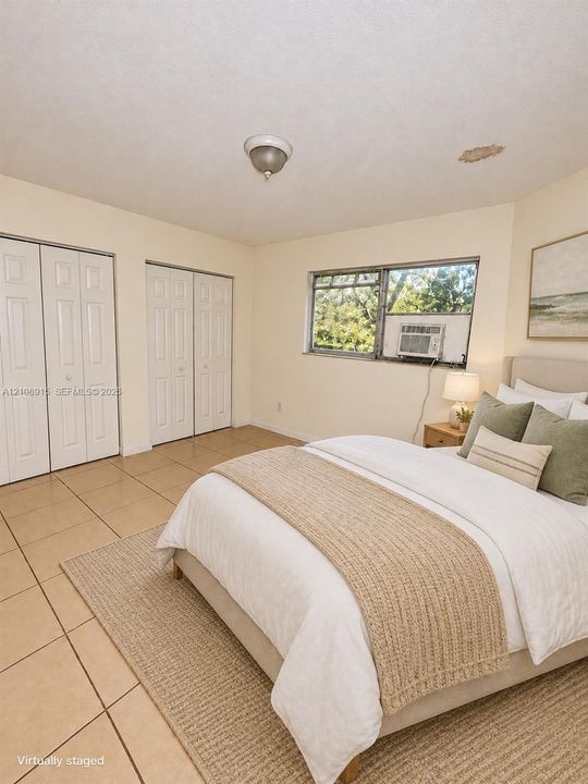 Interior room featuring neutral wall tones, large-format tile flooring, and dual bi-fold door closets