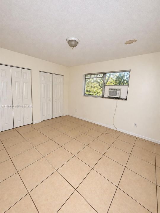 Neutral-toned tile flooring, dual bi-fold closets, and a large horizontal window