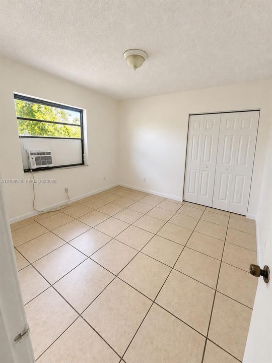 Neutral-toned tile flooring, white bi-fold closet doors, and a single-pane window