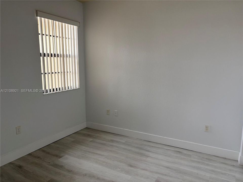 Room featuring neutral interior wall paint, wood-finish flooring, and a window with vertical blinds