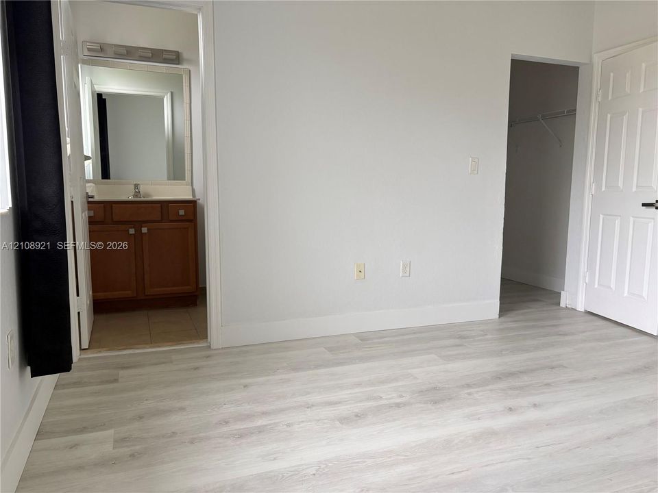 Wood-finish flooring, multi-panel interior door, and walk-in closet featuring wire shelving