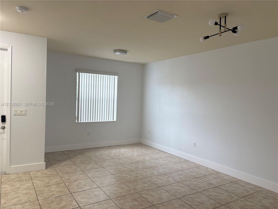 Neutral-toned ceramic tile flooring, multi-arm structural light fixture, and vertical window blinds