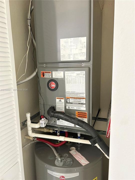 Utility closet containing a Rheem HVAC air handler unit and a Rheem water heater