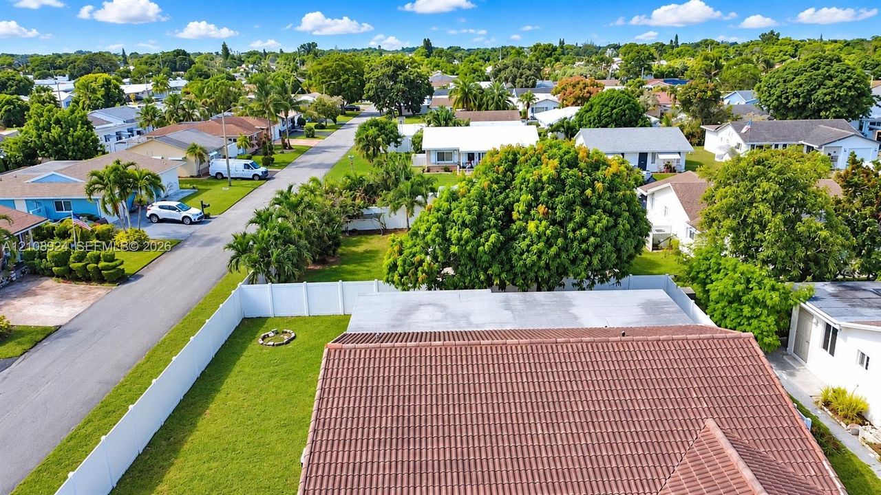 Aerial perspective featuring a tile roof, expansive fenced-in green space, and established mature landscaping