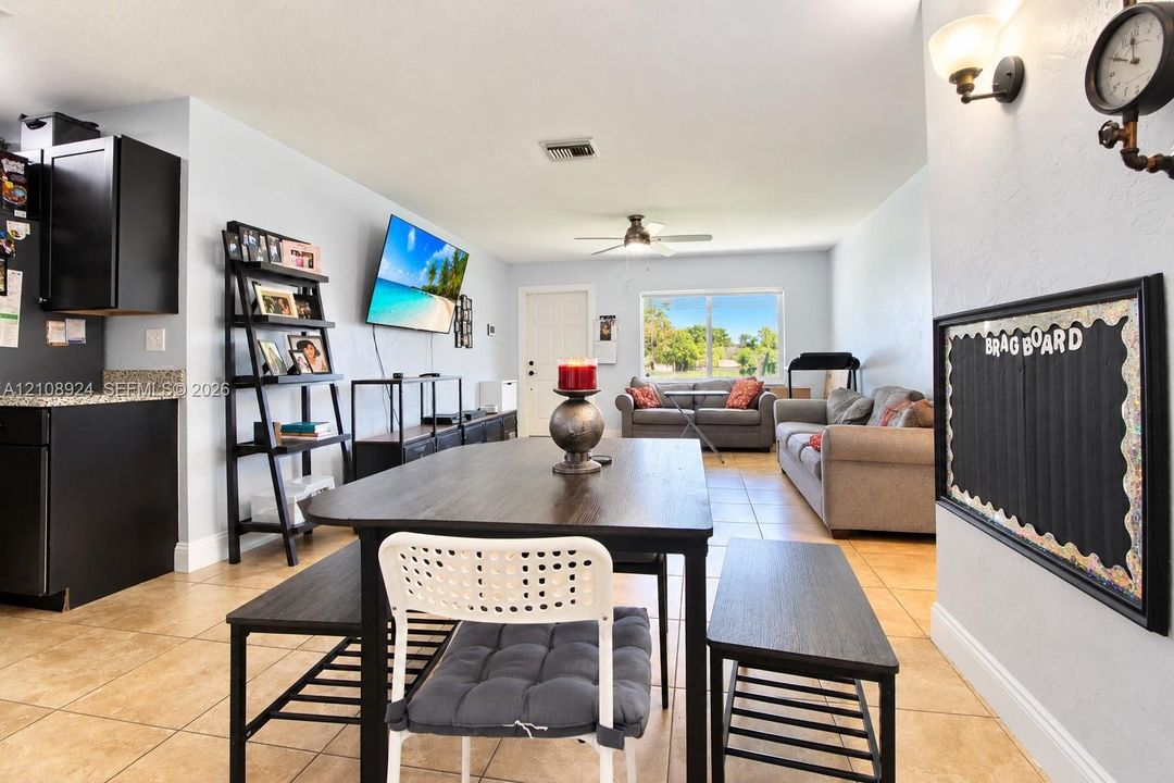 Open-concept living space featuring ceramic tile flooring, ceiling fan, natural light from large windows, and built-in wall-mounted light fixtures
