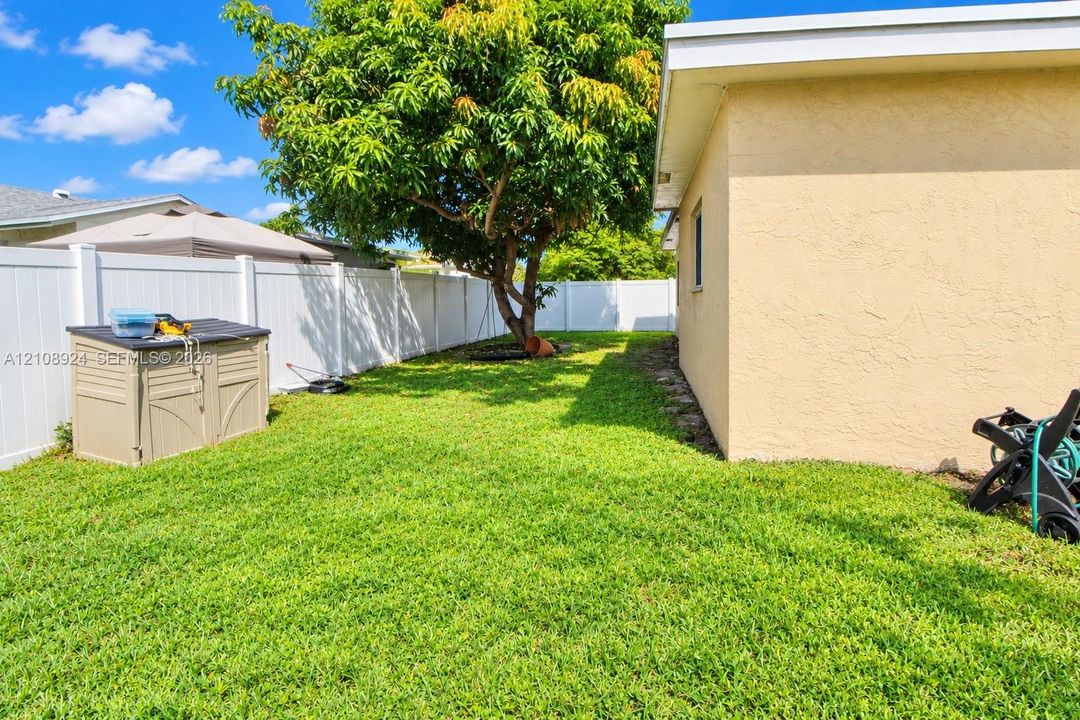 Backyard featuring a green lawn, privacy fencing, and a mature tree