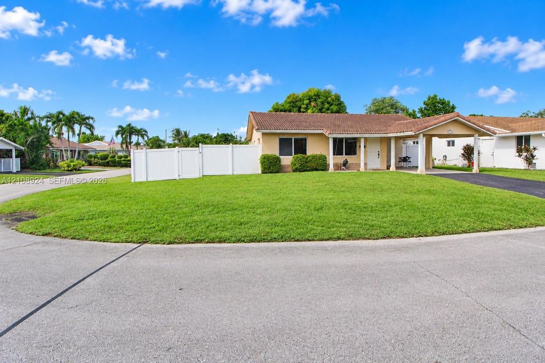 Single-story residence featuring a tile roof, an attached covered carport, and a white vinyl privacy fence