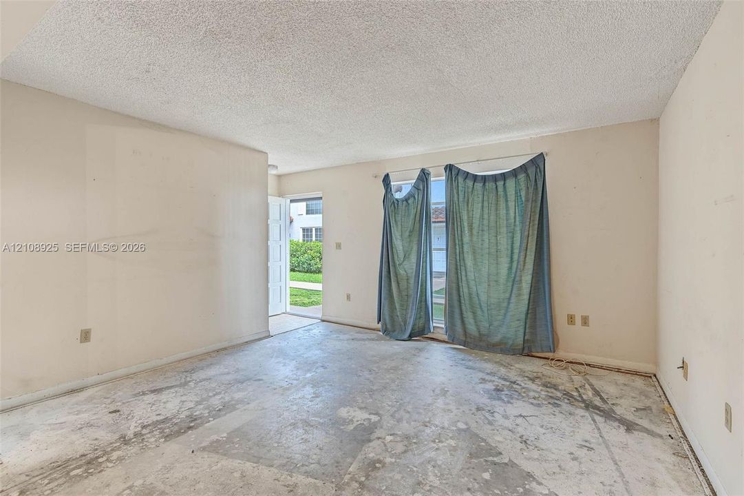 Room featuring a glass sliding door, textured ceiling, and an exterior door opening