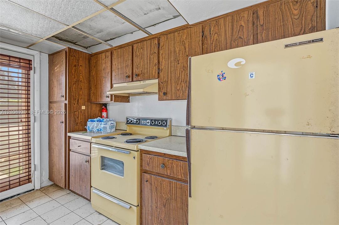 Kitchen featuring wood-finish cabinetry, a built-in range, a full-size refrigerator, tiled flooring, and a glass-paneled exterior door