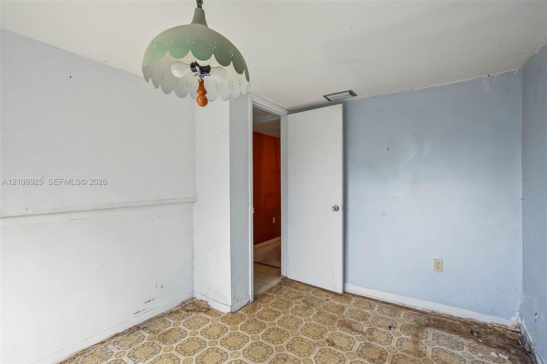 Interior space featuring geometric-patterned sheet flooring, a scalloped pendant light fixture, and a single-panel interior door